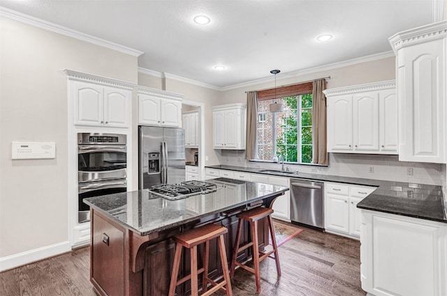 kitchen featuring appliances with stainless steel finishes, dark hardwood / wood-style flooring, a kitchen island, white cabinetry, and hanging light fixtures