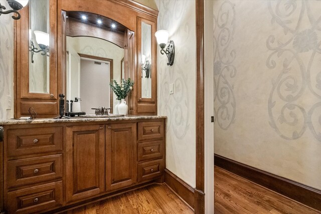 bathroom featuring baseboards, wood finished floors, and vanity