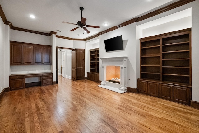 unfurnished living room featuring ceiling fan, baseboards, light wood-style floors, a lit fireplace, and built in study area