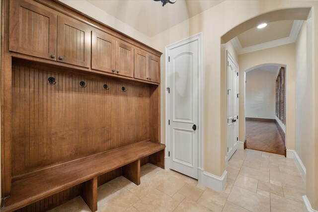 mudroom with baseboards, arched walkways, crown molding, and recessed lighting