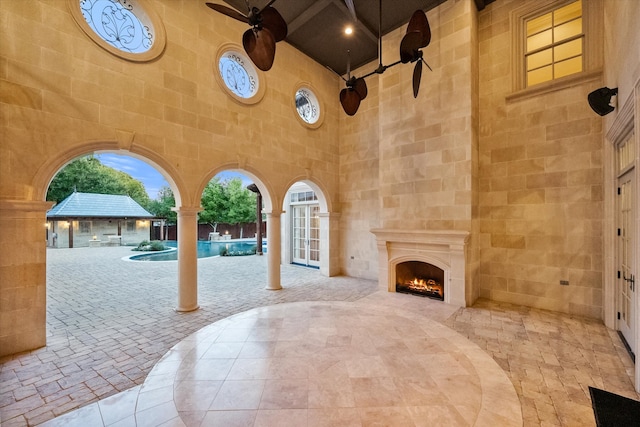 exterior space featuring ceiling fan and a lit fireplace