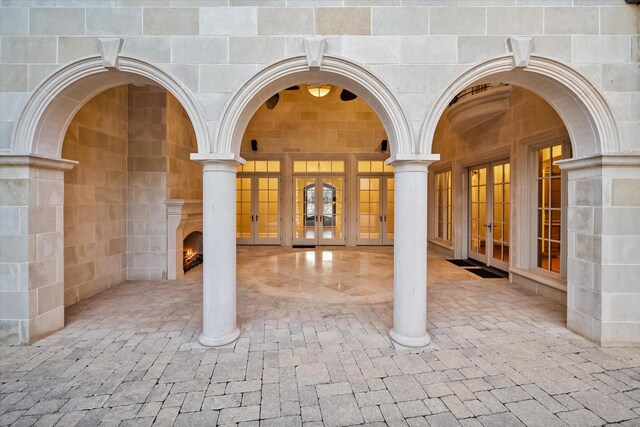 doorway to property with a warm lit fireplace and french doors