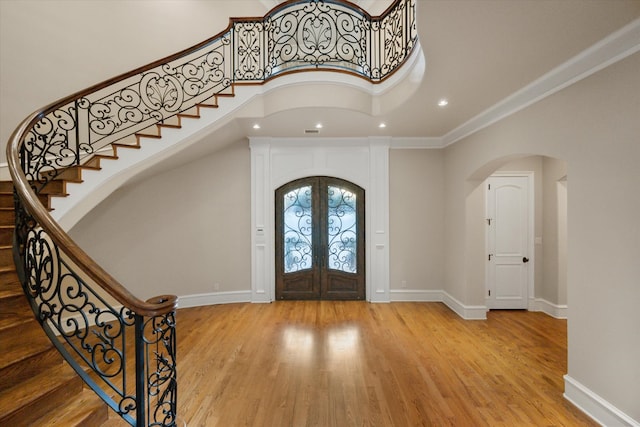 entryway featuring arched walkways, french doors, baseboards, and wood finished floors