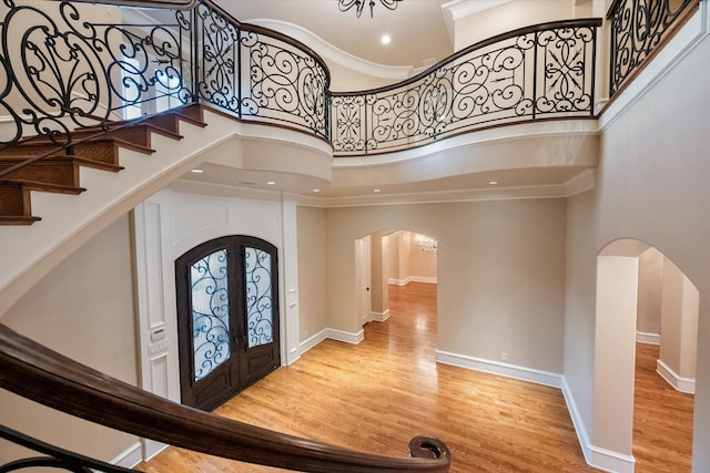 entryway featuring arched walkways, a high ceiling, wood finished floors, and baseboards