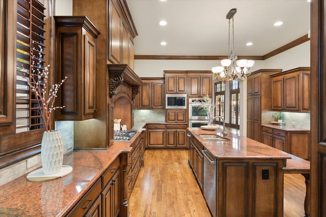 kitchen featuring stone counters, appliances with stainless steel finishes, a sink, and ornamental molding