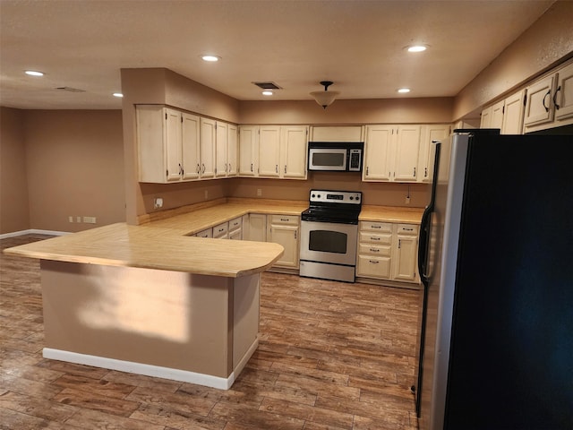 kitchen with stainless steel appliances, kitchen peninsula, and white cabinets