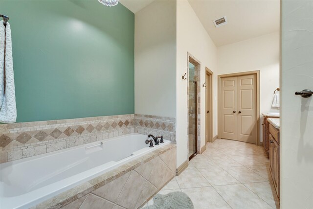 bathroom featuring vanity, tile patterned flooring, and a relaxing tiled tub