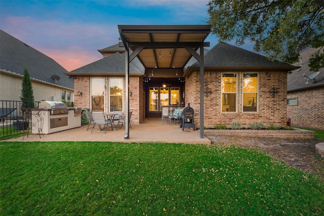 back house at dusk featuring a yard, area for grilling, and a patio