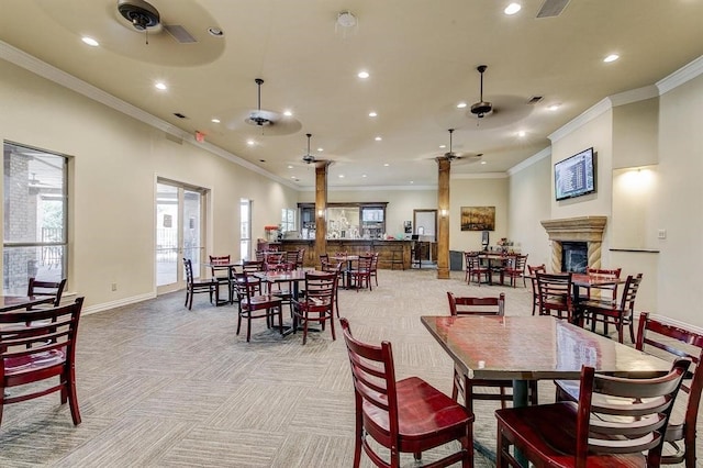 carpeted dining space featuring ceiling fan, a fireplace, and ornamental molding