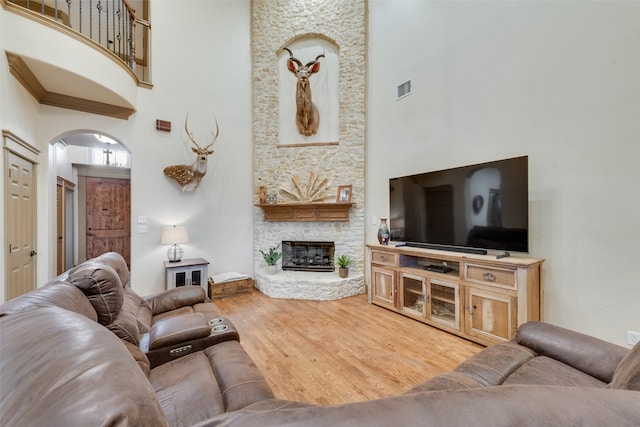 living room featuring hardwood / wood-style flooring, a high ceiling, and a fireplace