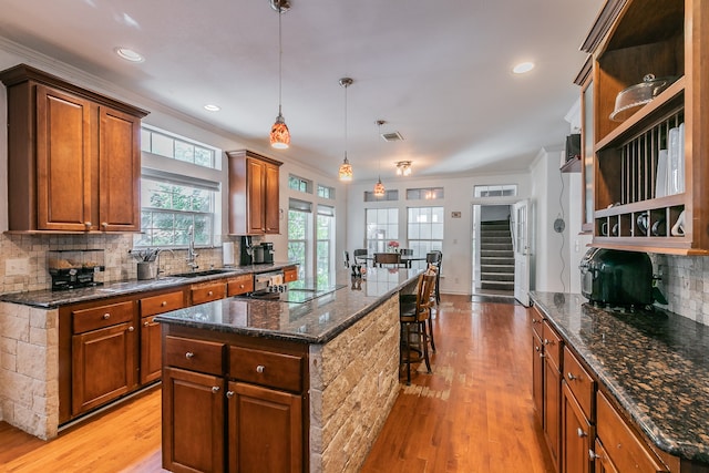 kitchen featuring decorative backsplash, decorative light fixtures, light hardwood / wood-style flooring, and a kitchen island