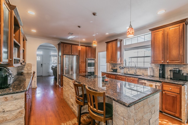 kitchen featuring a breakfast bar, sink, decorative light fixtures, hardwood / wood-style floors, and a kitchen island