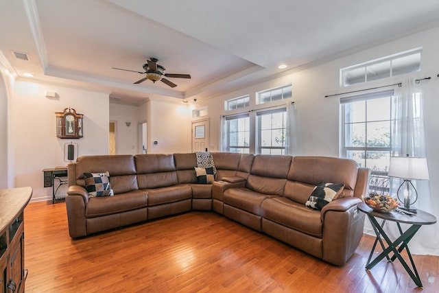 living room with a tray ceiling, ceiling fan, wood-type flooring, and ornamental molding