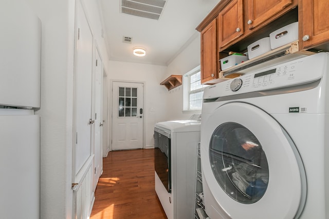 laundry room with cabinets, dark hardwood / wood-style floors, crown molding, and washing machine and clothes dryer