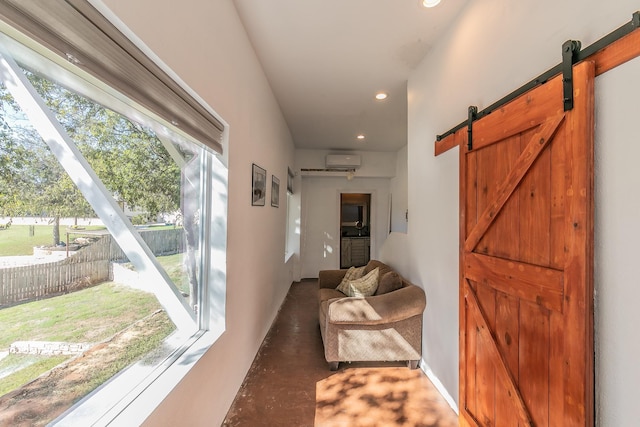 hallway featuring a wall mounted AC, a wealth of natural light, and a barn door