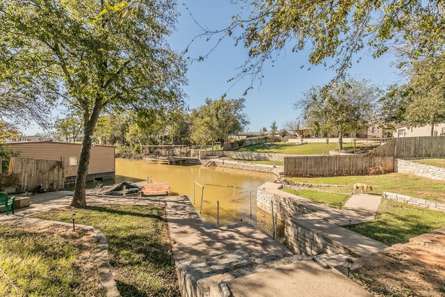 view of community featuring a lawn, a water view, and a boat dock