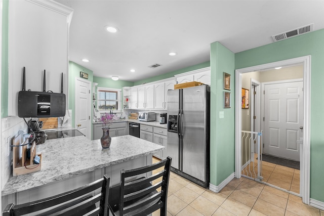 kitchen with decorative backsplash, light tile patterned floors, white cabinetry, and black appliances