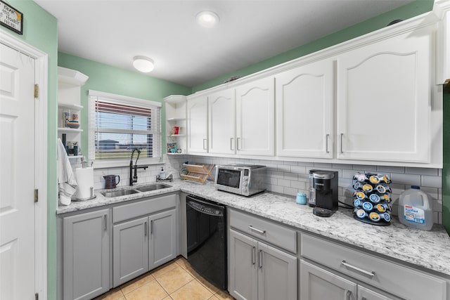 kitchen with gray cabinetry, sink, light tile patterned floors, black dishwasher, and light stone counters