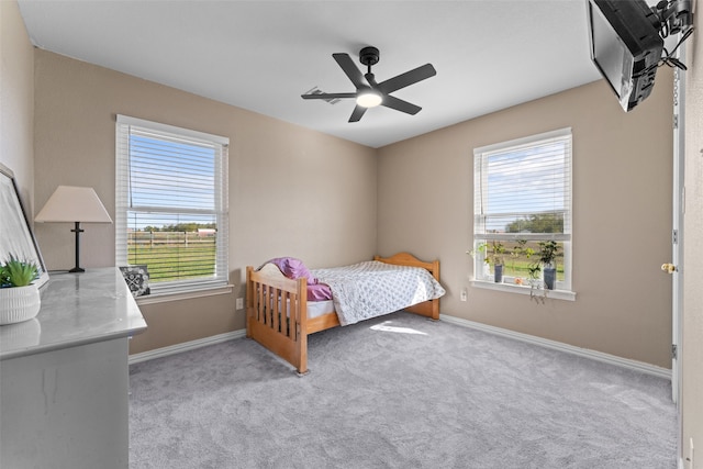 bedroom with light colored carpet, multiple windows, and ceiling fan