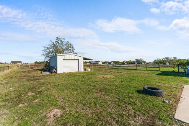 view of yard with a garage, a rural view, and an outdoor structure