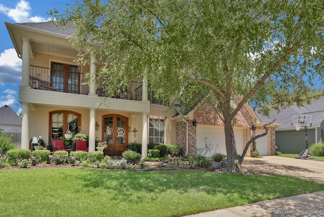 view of front of property featuring french doors, a balcony, a garage, and a front lawn