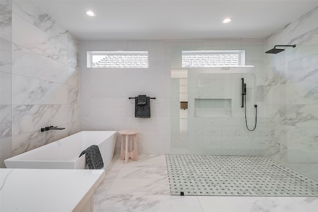 bathroom featuring a healthy amount of sunlight, shower with separate bathtub, and tile walls