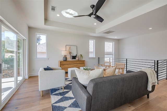 living room with light hardwood / wood-style floors, ceiling fan, and a healthy amount of sunlight