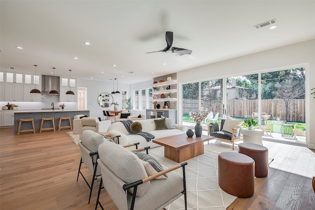 living room with ceiling fan, light hardwood / wood-style flooring, and sink