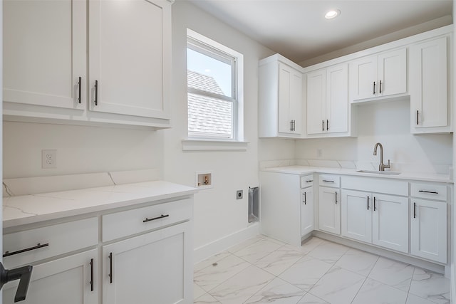 kitchen with white cabinetry, sink, and light stone countertops