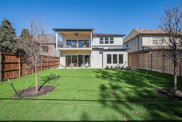 rear view of property featuring a yard, ceiling fan, and a balcony