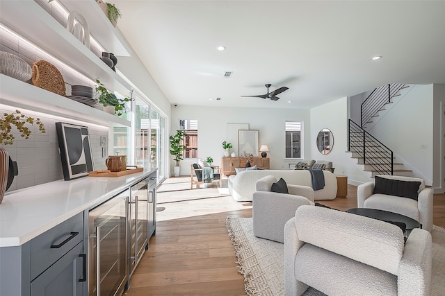 living room featuring bar, wine cooler, ceiling fan, and light hardwood / wood-style floors