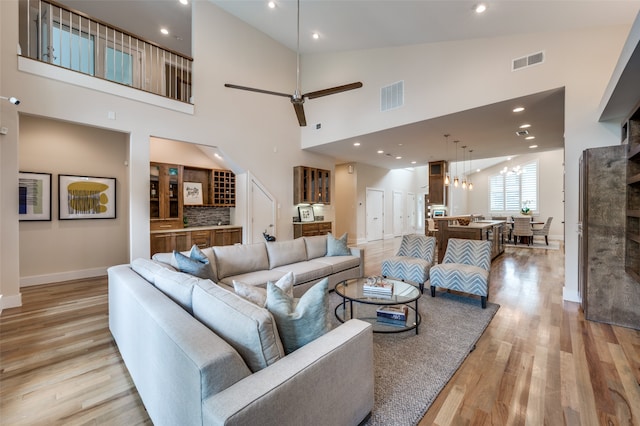 living room with light hardwood / wood-style floors, ceiling fan, and a high ceiling