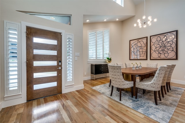 dining area featuring a chandelier, light hardwood / wood-style floors, and a high ceiling