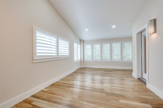 spare room with lofted ceiling and light wood-type flooring