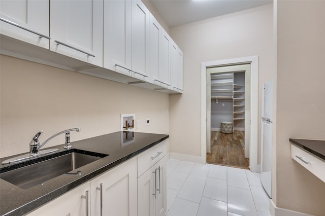 kitchen featuring light tile patterned flooring, dark stone counters, sink, and white cabinets