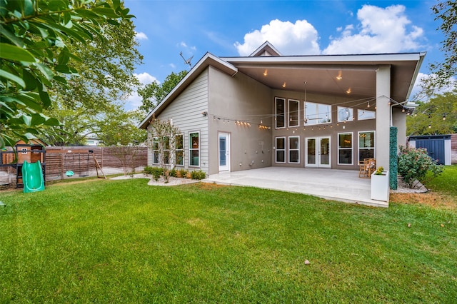 rear view of house with a yard, a playground, and a patio area