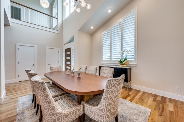 dining space featuring a high ceiling, light hardwood / wood-style floors, and a notable chandelier