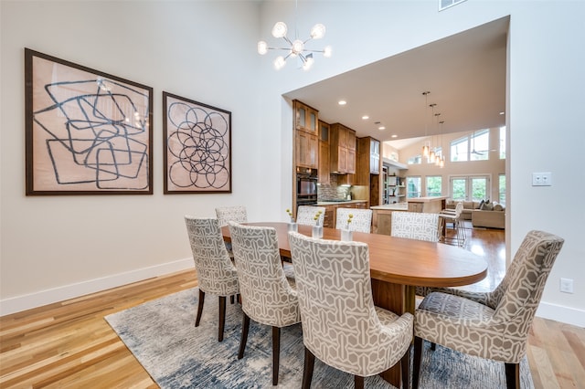 dining room featuring a chandelier, light hardwood / wood-style flooring, and a high ceiling