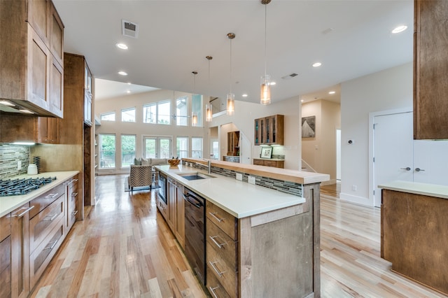 kitchen featuring pendant lighting, sink, decorative backsplash, a large island, and light hardwood / wood-style floors