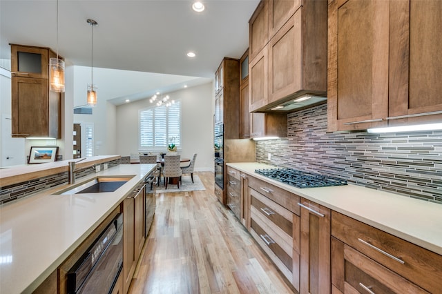 kitchen with sink, premium range hood, hanging light fixtures, backsplash, and stainless steel gas stovetop