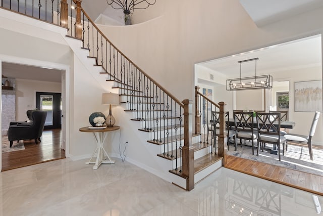 stairway with a high ceiling, hardwood / wood-style flooring, an inviting chandelier, and a healthy amount of sunlight