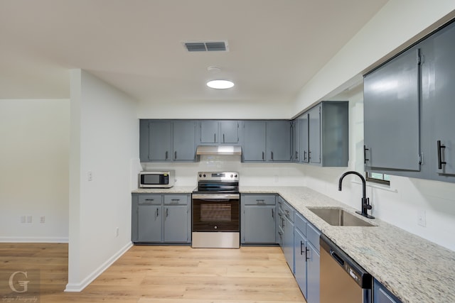 kitchen featuring light stone countertops, sink, stainless steel appliances, and light hardwood / wood-style floors