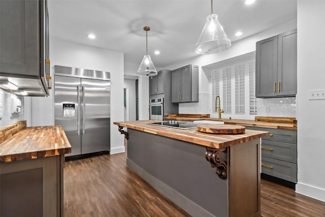 kitchen featuring a kitchen island with sink, appliances with stainless steel finishes, and wooden counters