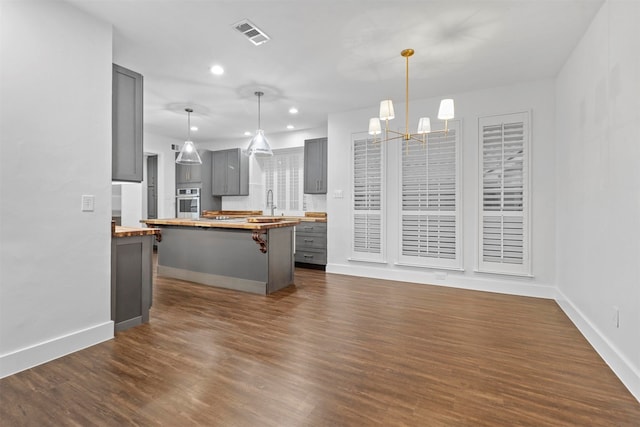 kitchen featuring a kitchen island, butcher block countertops, gray cabinets, oven, and dark hardwood / wood-style floors