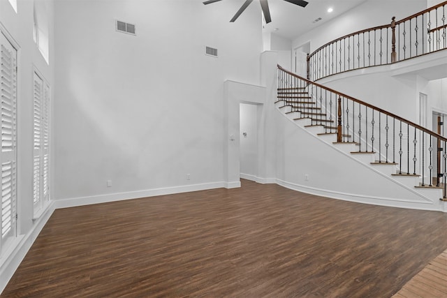 unfurnished living room with ceiling fan, dark hardwood / wood-style flooring, and a towering ceiling