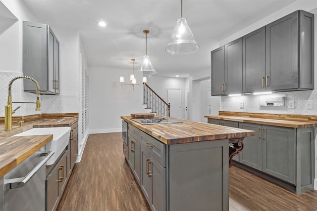 kitchen featuring gray cabinetry, hanging light fixtures, and wood counters