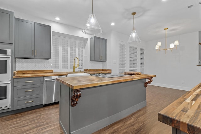 kitchen with gray cabinetry, sink, stainless steel dishwasher, and butcher block counters