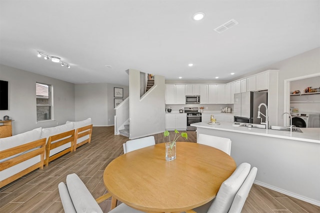 dining area featuring light hardwood / wood-style floors, washer / clothes dryer, and sink