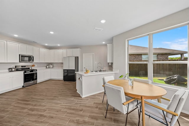 kitchen featuring sink, white cabinetry, stainless steel appliances, and light hardwood / wood-style flooring