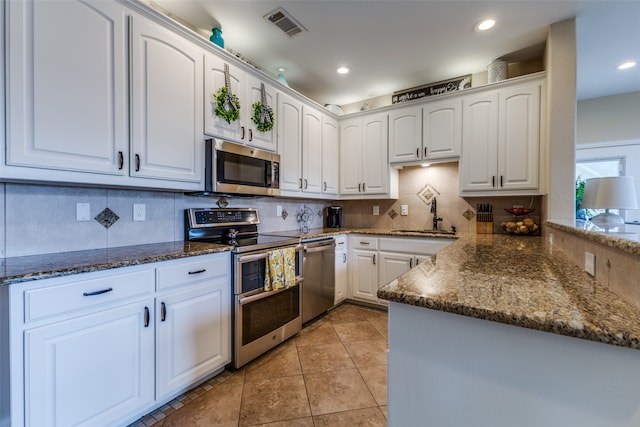 kitchen with white cabinets, dark stone countertops, sink, and stainless steel appliances